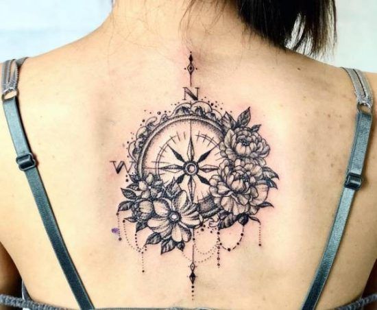 a woman's back with a compass and flowers on it