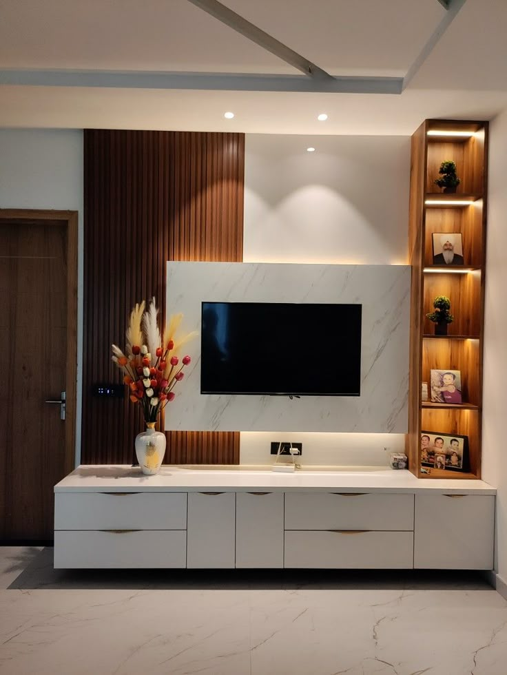 a tv mounted on the wall in a living room with white cabinets and marble flooring