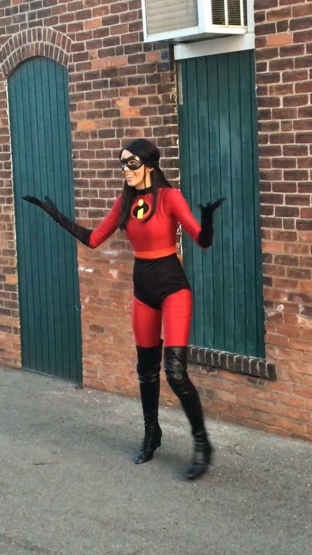 a woman in a red and black costume is walking down the street with her arms out