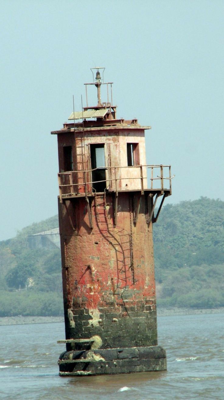 an old rusted tower sitting in the middle of water