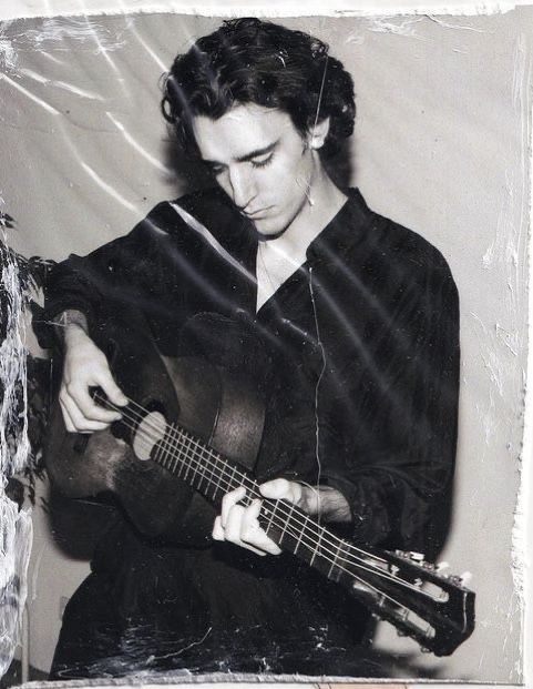 a black and white photo of a man playing a guitar