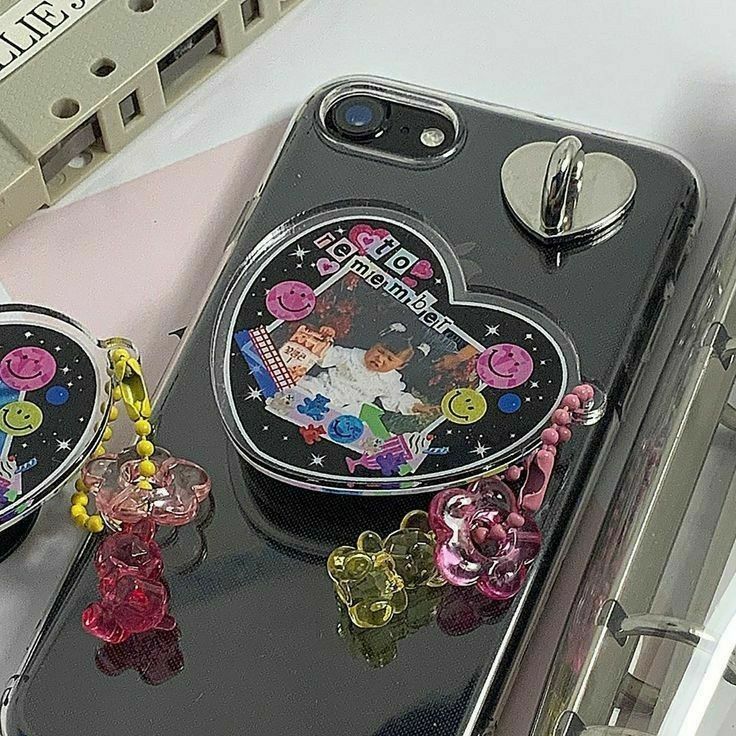 a cell phone case with an image of a couple on it and some charms attached to the back