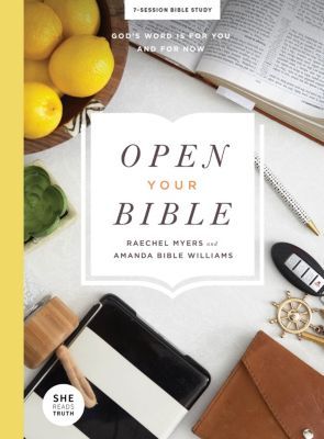 an open bible next to other items on a table with lemons, books and pens