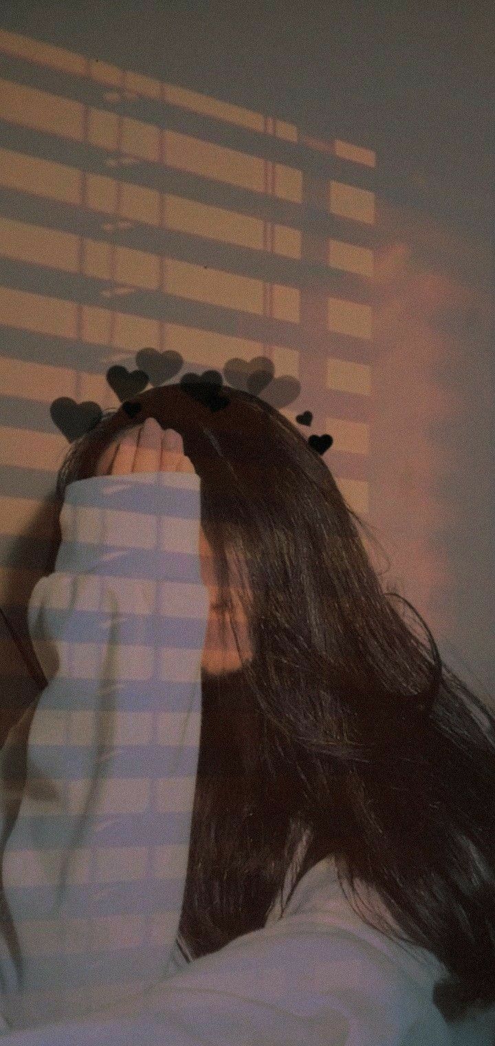 a woman covering her face with hair combs in front of a window covered by blinds