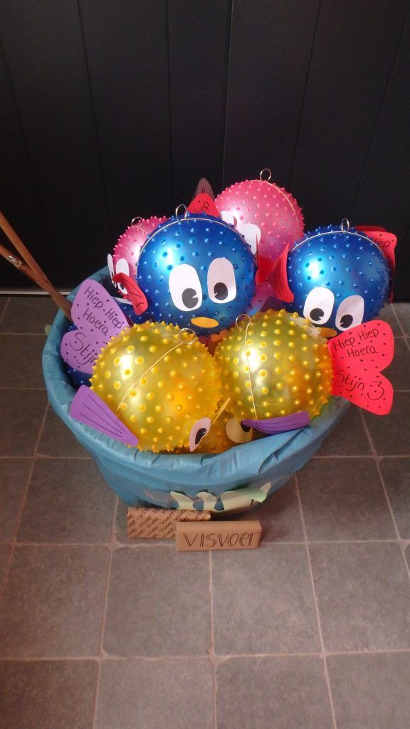 a blue bowl filled with lots of balloons and some birds on top of each other