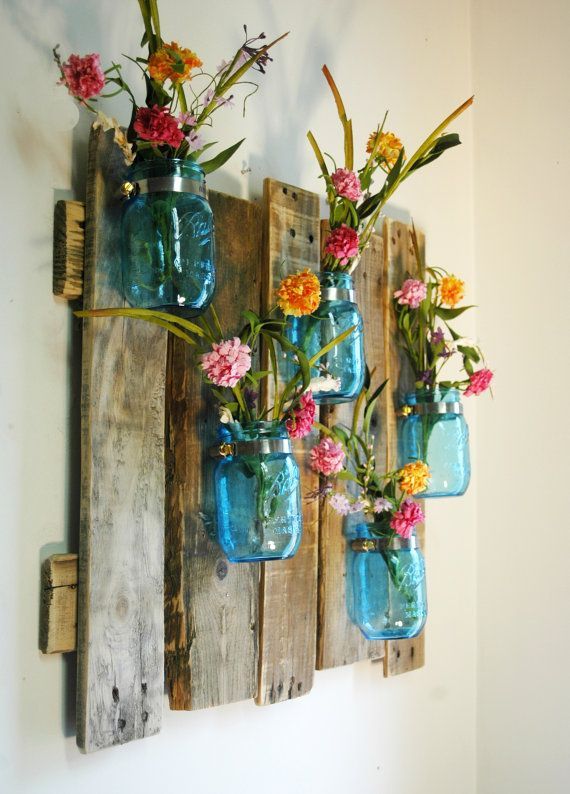 mason jars filled with flowers hanging on a wall