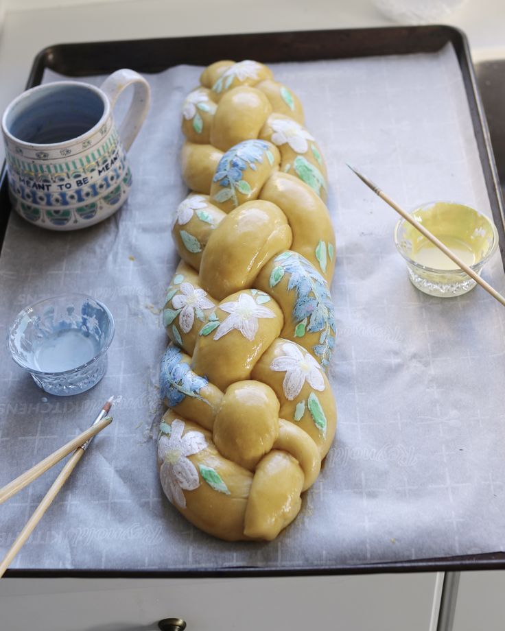 a loaf of bread sitting on top of a pan covered in icing next to two cups