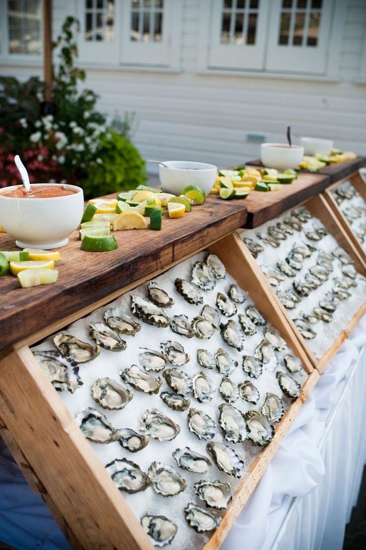 an assortment of food is displayed on a long wooden table with bowls and plates in front of it