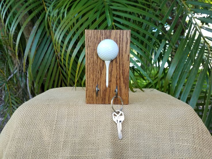 a wooden key holder with a golf ball on it and a pair of keys hanging from the front