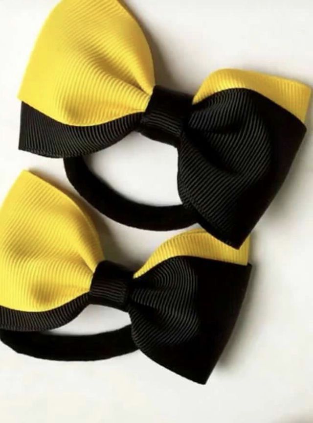 two black and yellow bow ties sitting on top of a white table next to each other