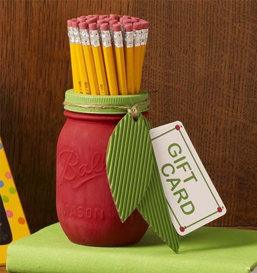 a jar with pencils in it sitting on top of a green table cloth next to a