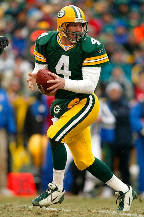 a football player in green and yellow uniform holding a ball while standing on the field