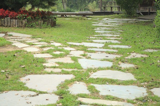 a stone path in the middle of a grassy area