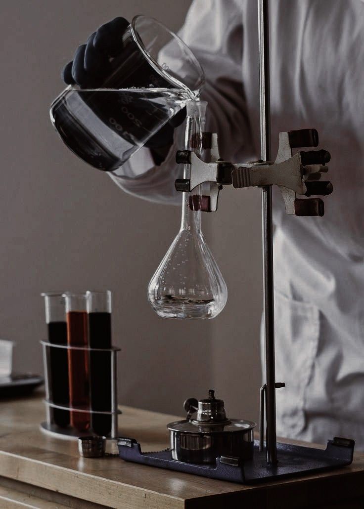 a person pouring liquid into a beakle