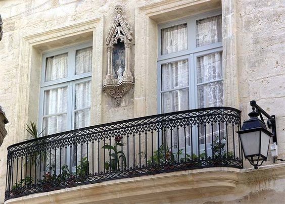 an ornate balcony with wrought iron balconies and statues on the side of it