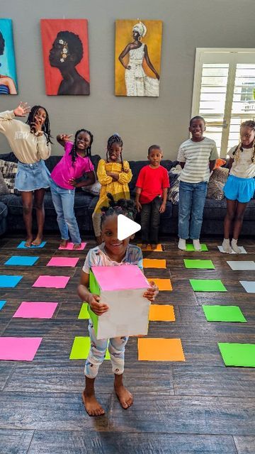 a group of children standing on top of a floor covered in colorful squares and shapes