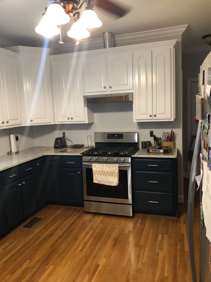 a kitchen with wood floors and white cabinets is pictured in this image, the ceiling fan has been turned on