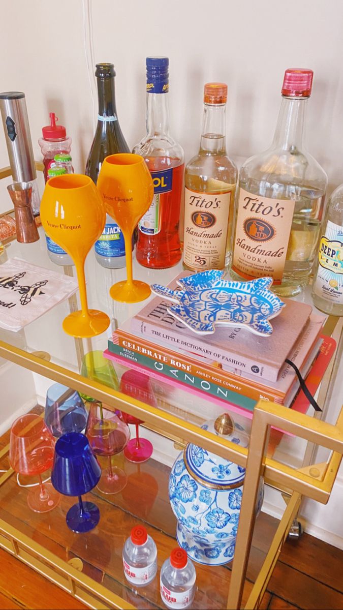 an assortment of liquor bottles and glasses on a bar cart