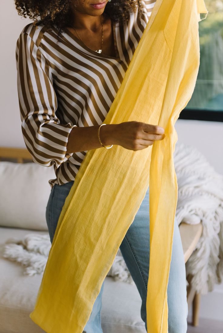 a woman in striped shirt holding yellow scarf