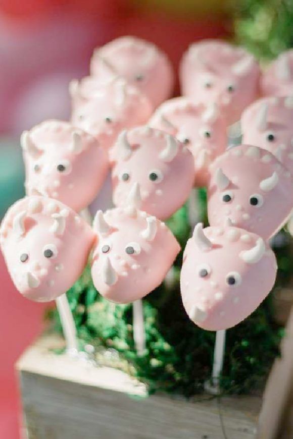 there are many pink pigs on sticks in the shape of flowers and grass, with little black dots