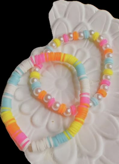 two bracelets made out of plastic beads on a white platter with flowers and leaves