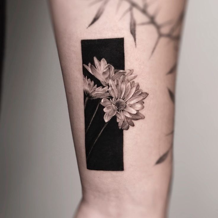 a black and white photo with flowers on the side of a woman's arm