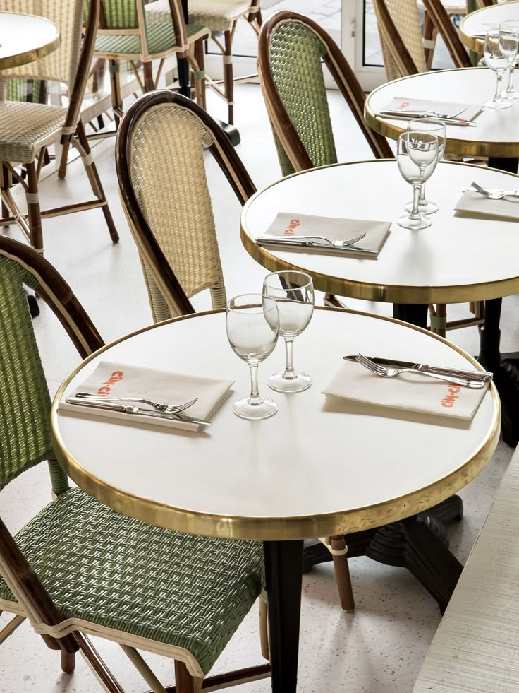 several tables and chairs with wine glasses on them