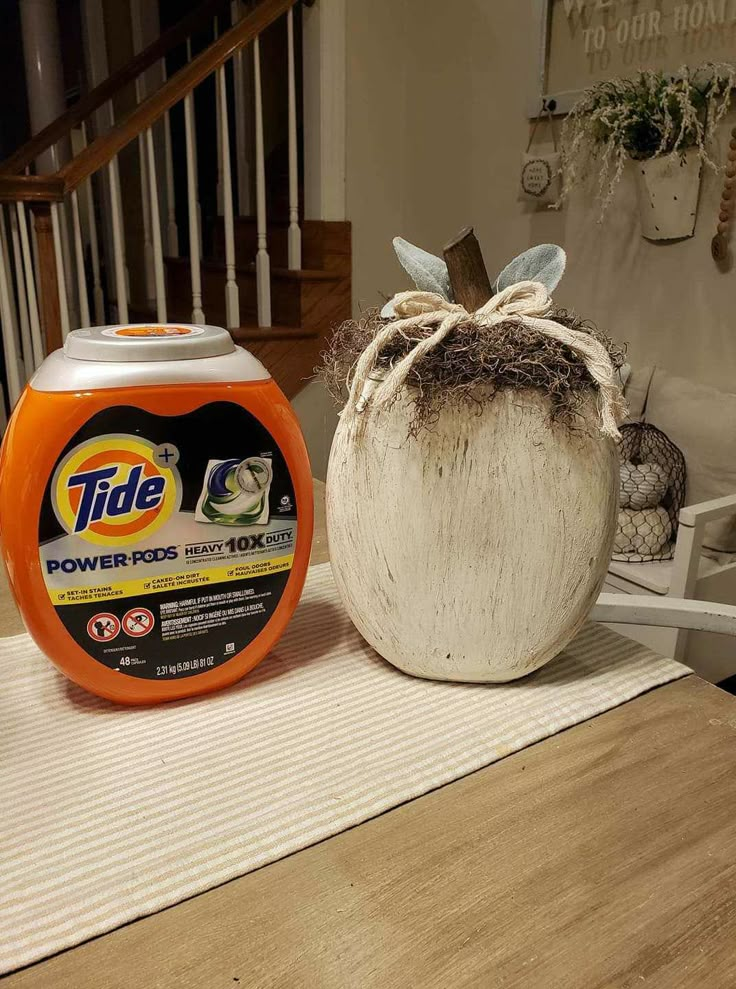 an orange and white container sitting on top of a table next to a bag of toilet paper