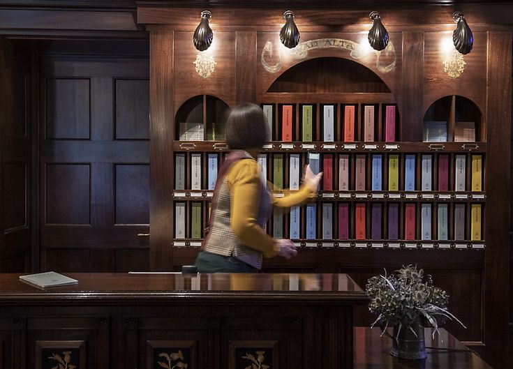 a woman standing in front of a book shelf filled with lots of books on top of a wooden desk