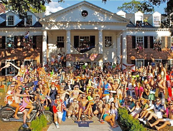 a large group of people posing in front of a house