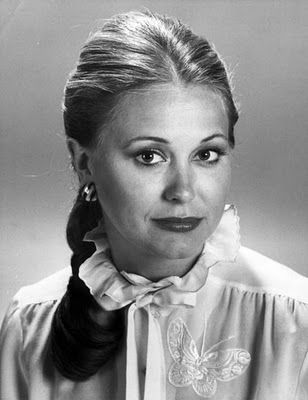 a woman with long hair wearing a blouse and earrings