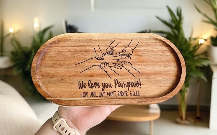 a person holding up a wooden tray that says, we love you mompool