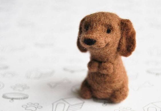 a small brown dog sitting on top of a white sheet with paw prints all over it