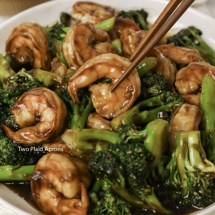 shrimp and broccoli stir fry with chopsticks in a white bowl