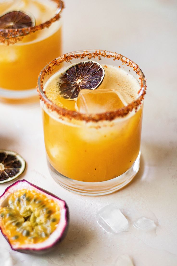 two glasses filled with orange juice and garnished with grapefruit on the side