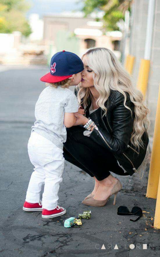 a woman kneeling down next to a little boy