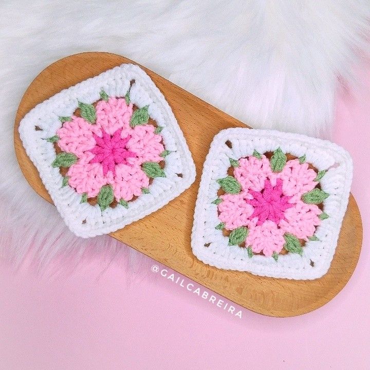 two crocheted coasters with pink flowers on them