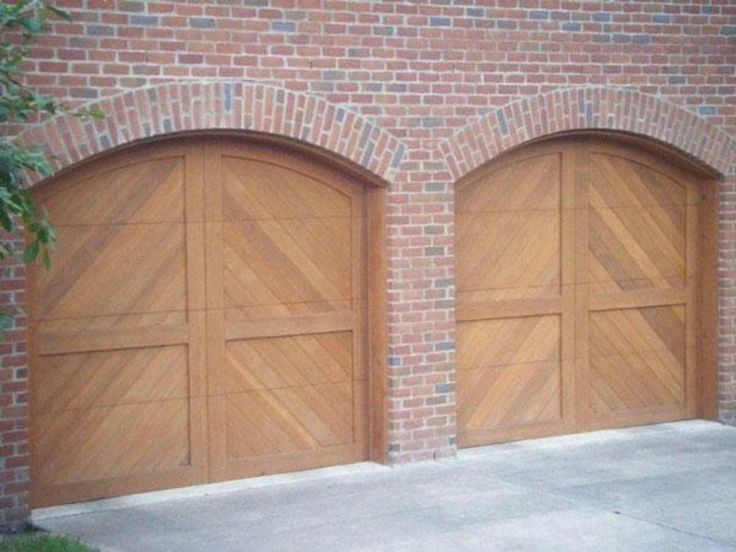 two wooden garage doors in front of a brick building