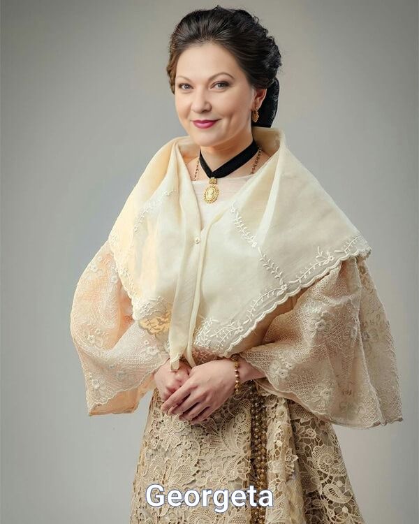 a woman in a dress and shawl posing for the camera with her hands on her hips