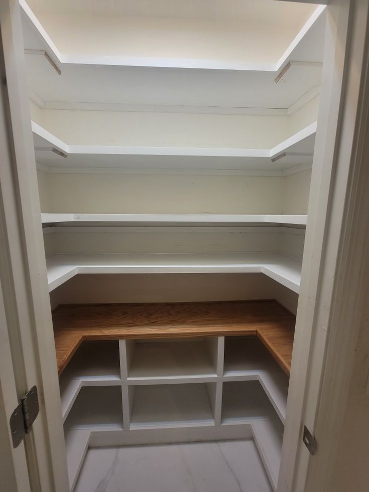 an empty walk - in closet with white shelves and wooden shelfs on each side