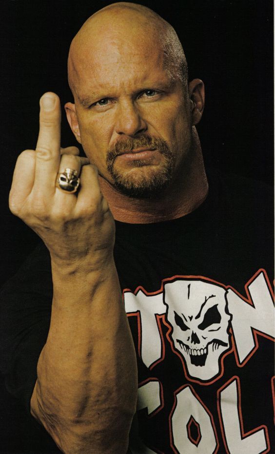 a bald man with a ring on his finger pointing to the side while wearing a skull t - shirt