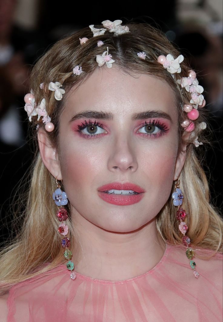 a woman with pink makeup and flowers in her hair, wearing flowery headpieces