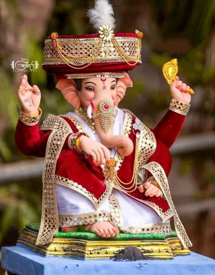 a statue of an elephant wearing a red and white outfit with a gold crown on it's head