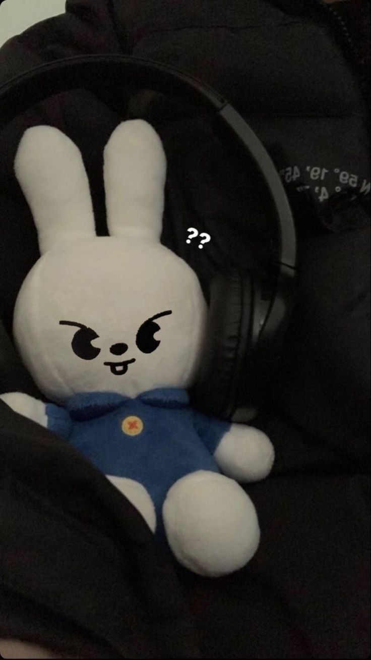 a stuffed animal with headphones on sitting in a black bag and listening to music