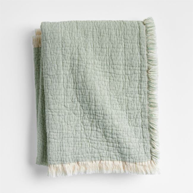 a green and white blanket with fringes on it