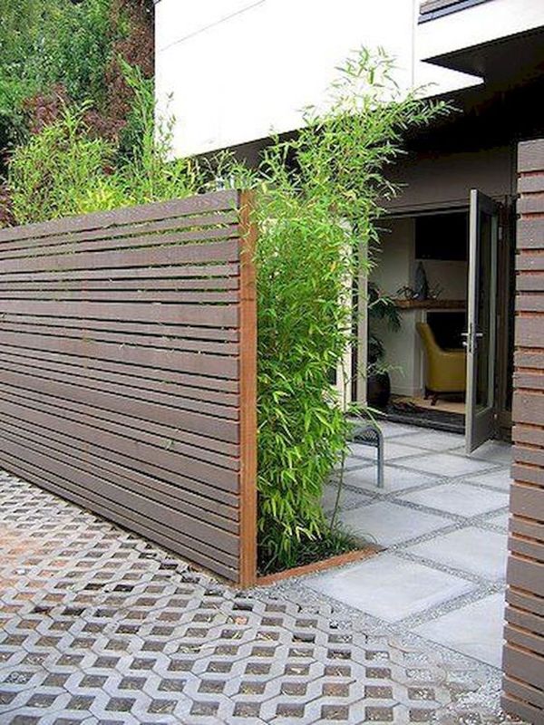 an outdoor area with a wooden fence and plants growing on the side of the building