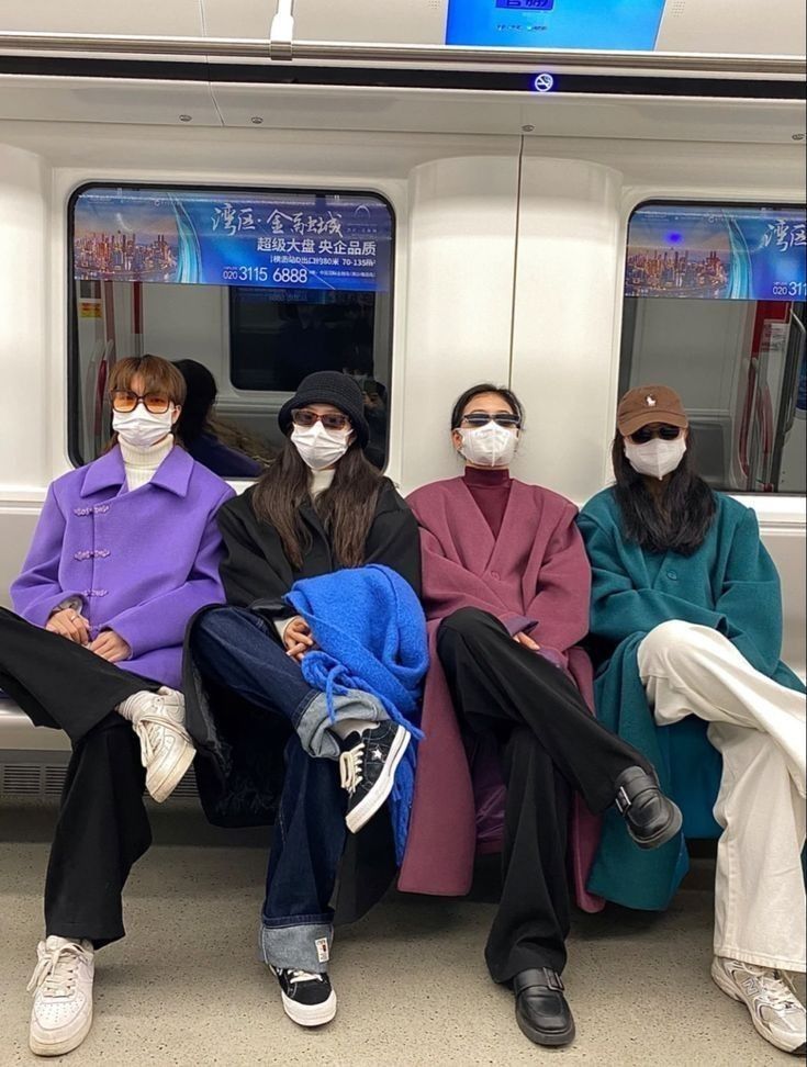 four people wearing masks sitting on a subway