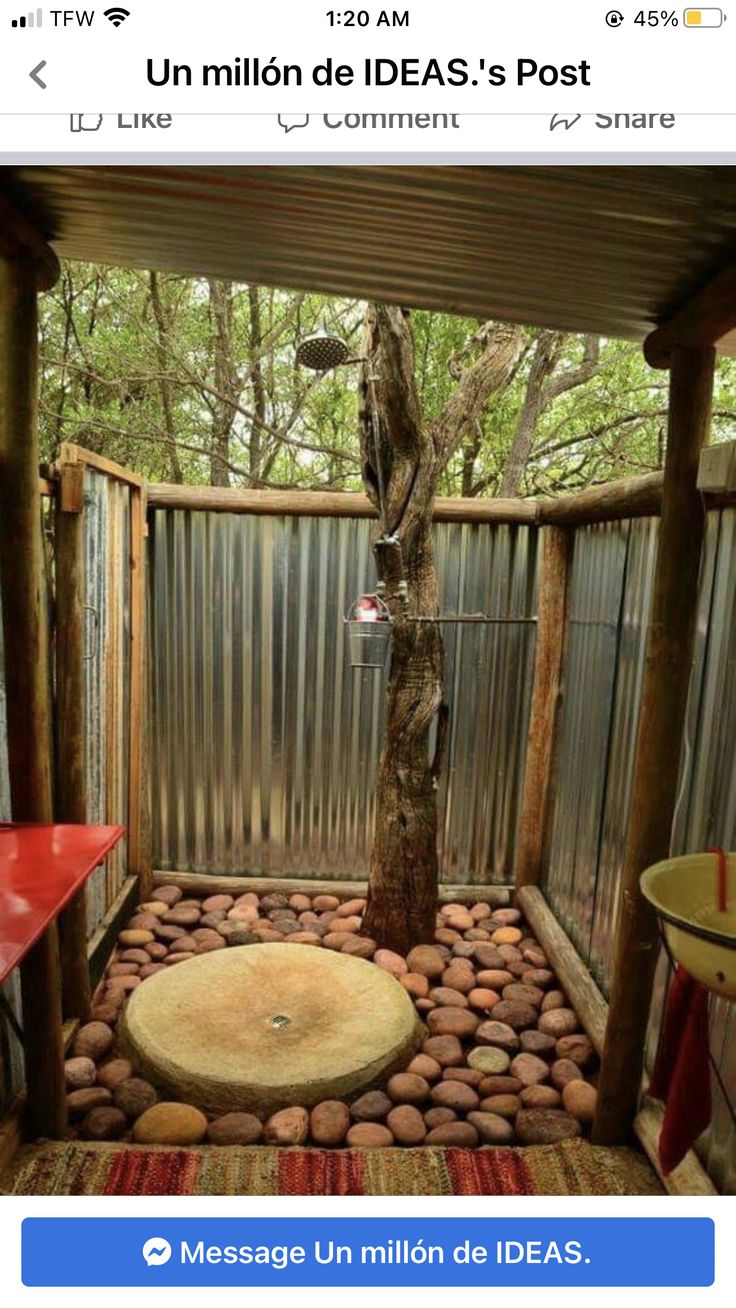 an outdoor shower with rocks in the ground and a tree growing out of it's center