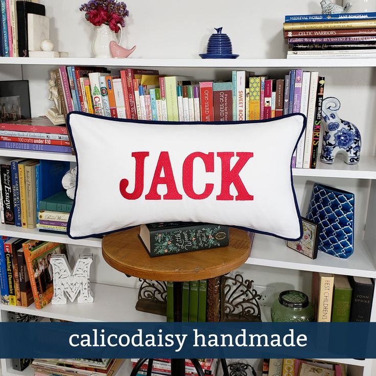 a pillow with the word jack on it in front of a bookshelf full of books