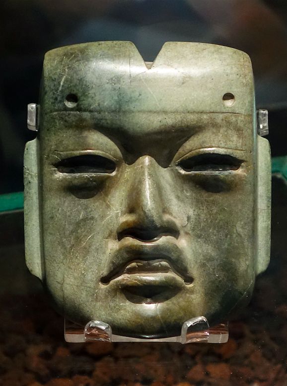 an ancient mask is on display in a glass case